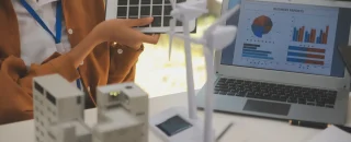 Simulação de projeto de energia com painel solar e turbinas eólicas em maquete, ilustrando análise comparativa entre geração distribuída ou mercado livre para empresas.