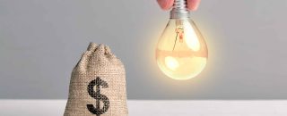 Representação de ganhar dinheiro com energia por assinatura com lâmpada acesa ao lado de um cofrinho com símbolo de dólar.