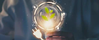 Mão segurando uma lâmpada com plugue e ícones de energia sustentável, ilustrando dúvidas comuns sobre se é possível ficar sem luz com energia por assinatura e os benefícios da fonte renovável.