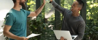 Dois profissionais comemorando parceria de sucesso, simbolizando estratégias colaborativas para captação de consumidores em energia solar.